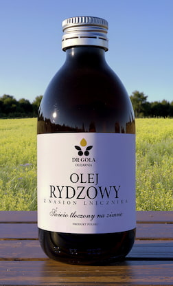 Butelka oleju rydzowego na tle lnianki siewnej